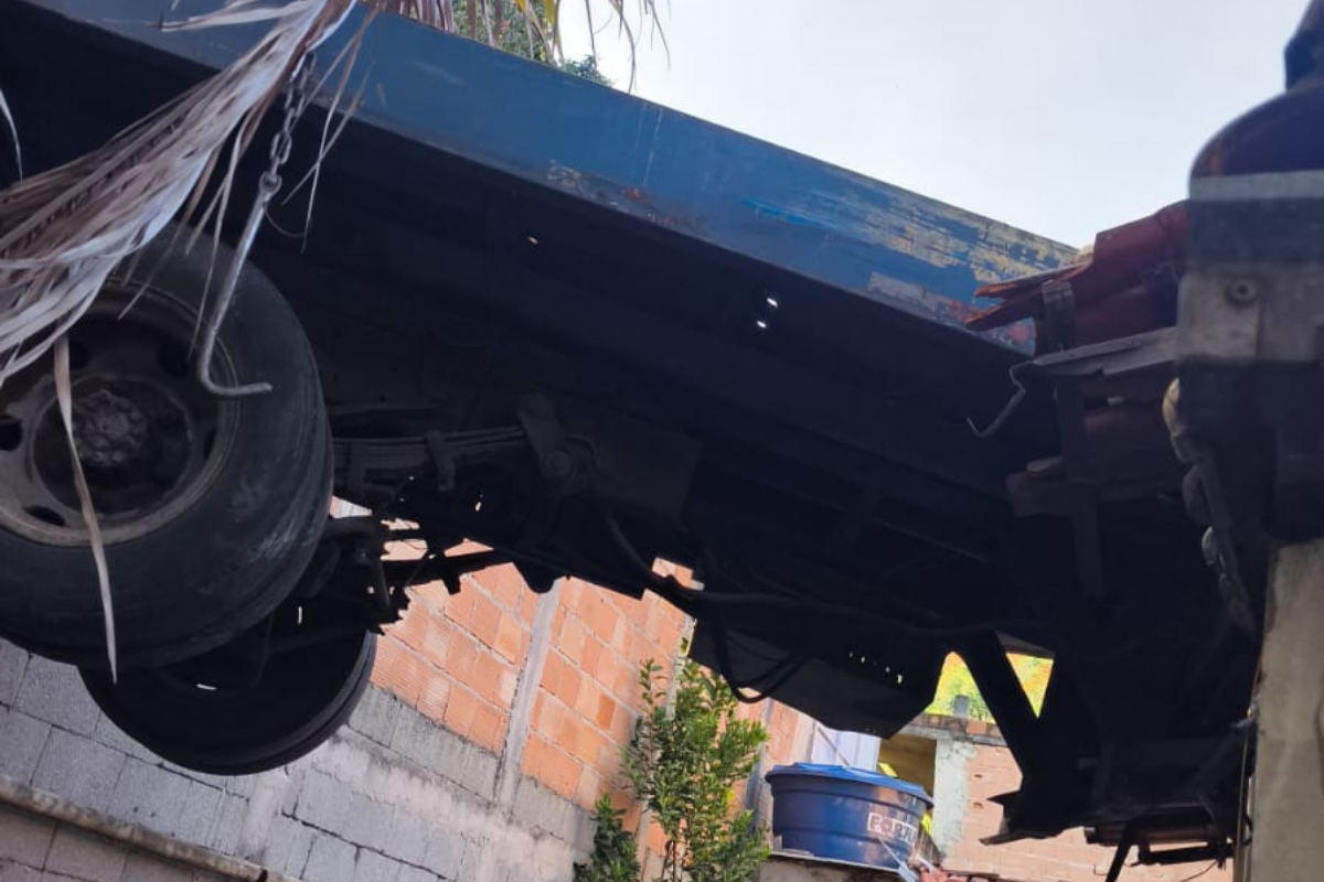 O veículo ficou parcialmente dependurado entre o passeio e o telhado da residência