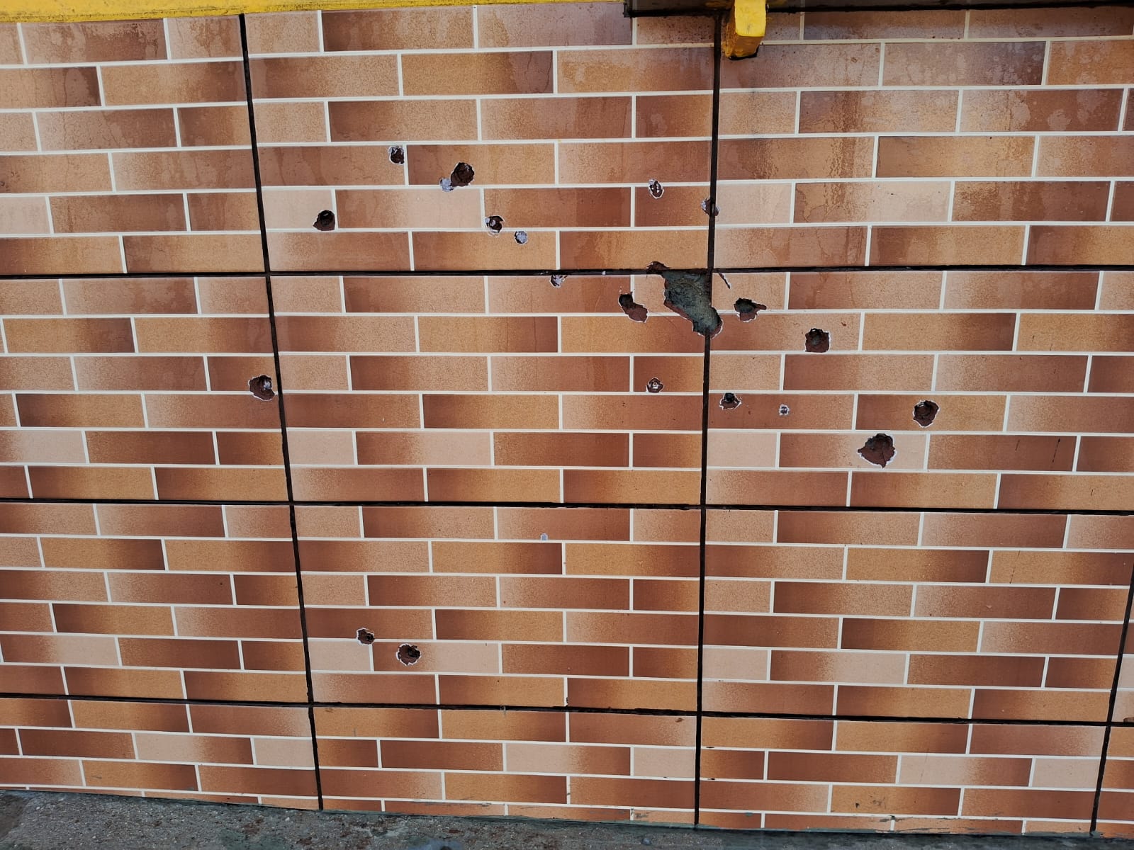Marcas dos tiros ficaram na parede de comércio na rua