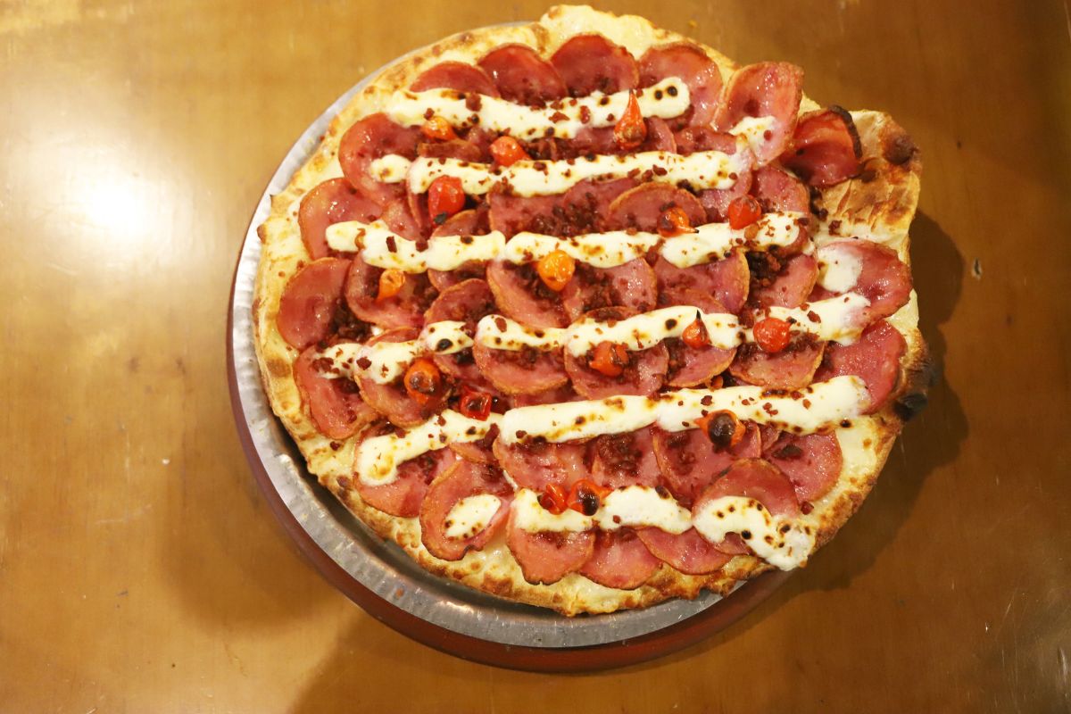 Receita leva calabresa, mussarela, cream cheese, molho de tomate, orégano, pimenta biquinho e uma leve camada de farofa de bacon, sendo servida à palito