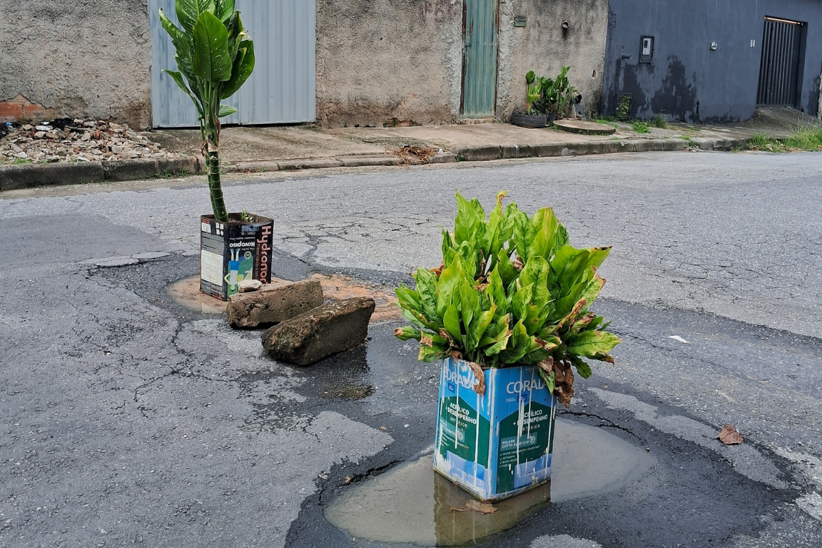 Vasos de plantas foram colocados por moradores para sinalizar e interditas parcialmente a rua Ângela Maria, no bairro Cruzeiro, devido a um buraco na via