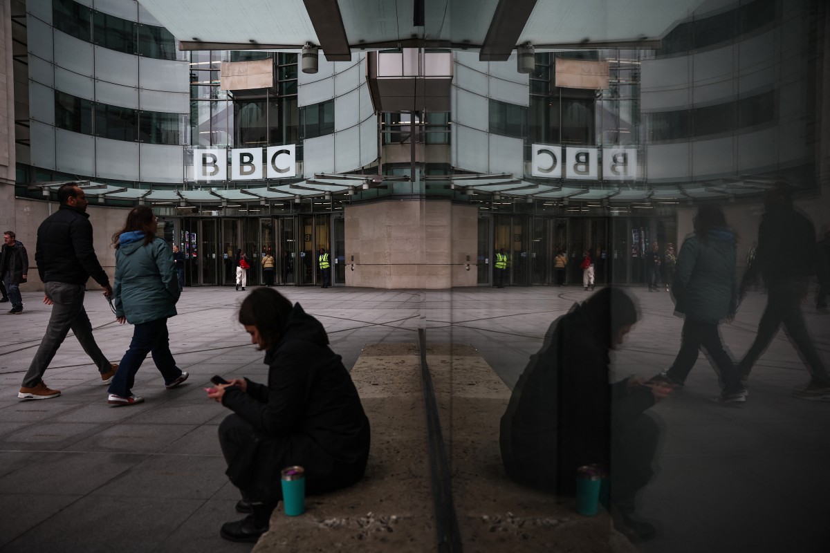 Pessoas caminham em frente à entrada dos escritórios da BBC em Londres, em 11 de novembro de 2025. (Photo by HENRY NICHOLLS / AFP)