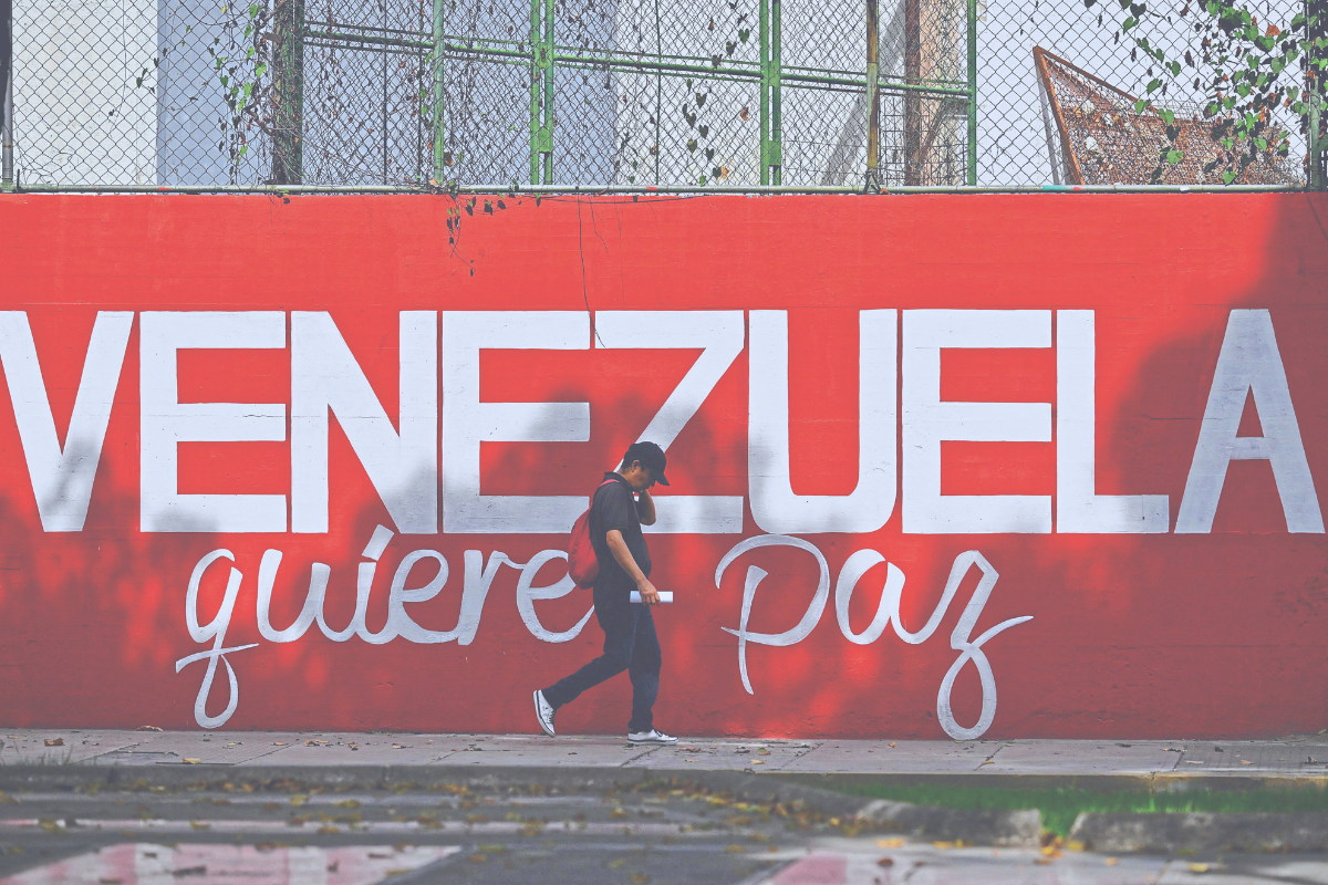 Pedestre passa por mural em Caracas, capital do país, que diz ‘A Venezuela quer paz’
